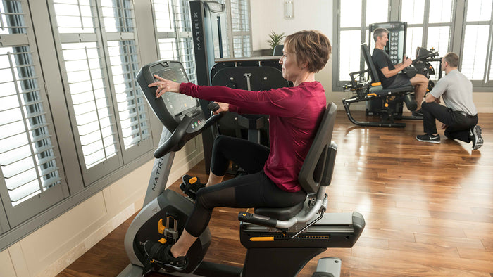 matrix medical female using console on recumbent indoor cycle bike