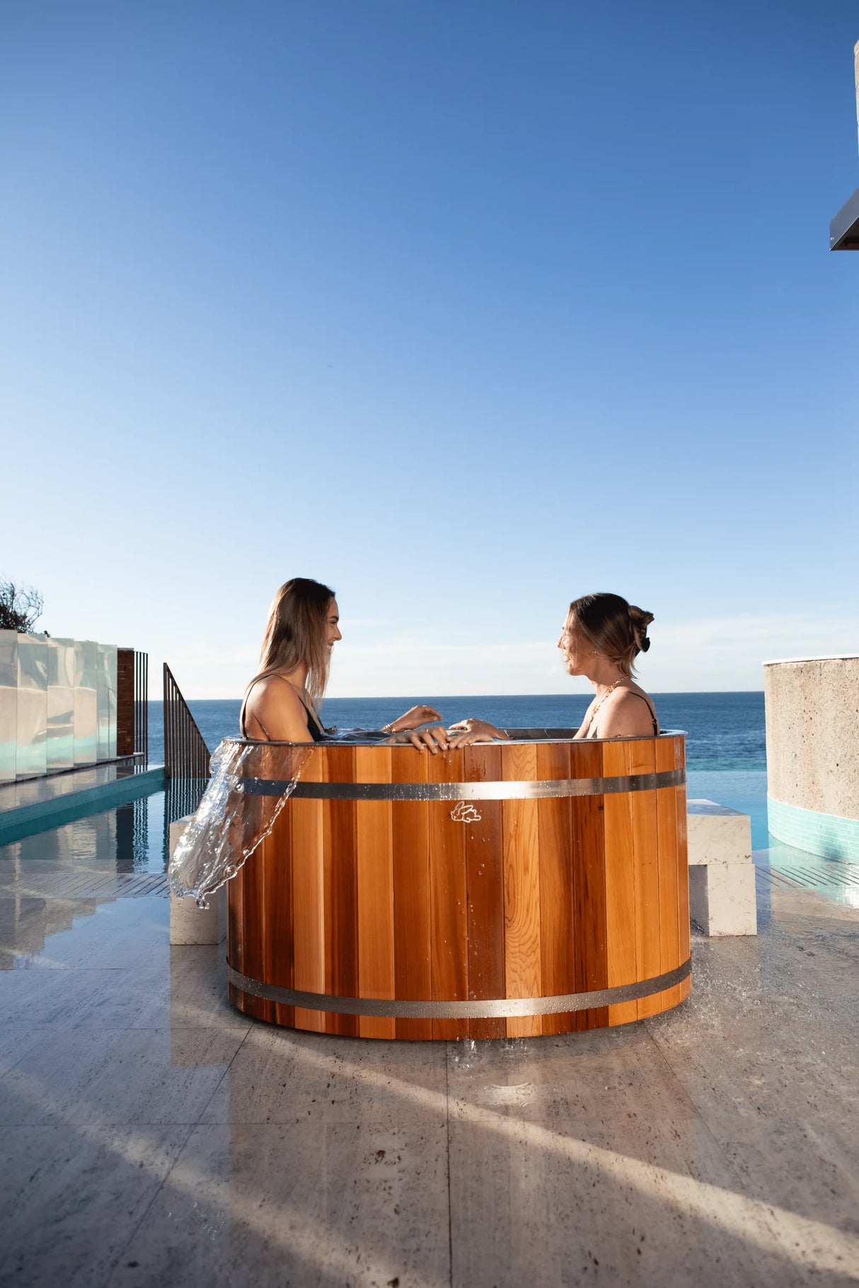 two girls in chill bunny ice bath - outdoors with ocean in background