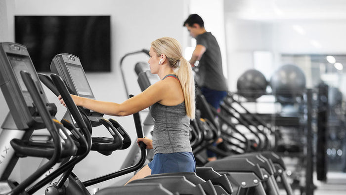 female using matrix elliptical and male using matrix climbmill in distance