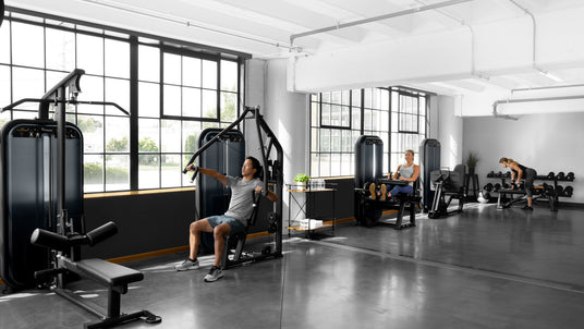 vision strength gym setting with male and females using various equipment - leg curl bench chest press