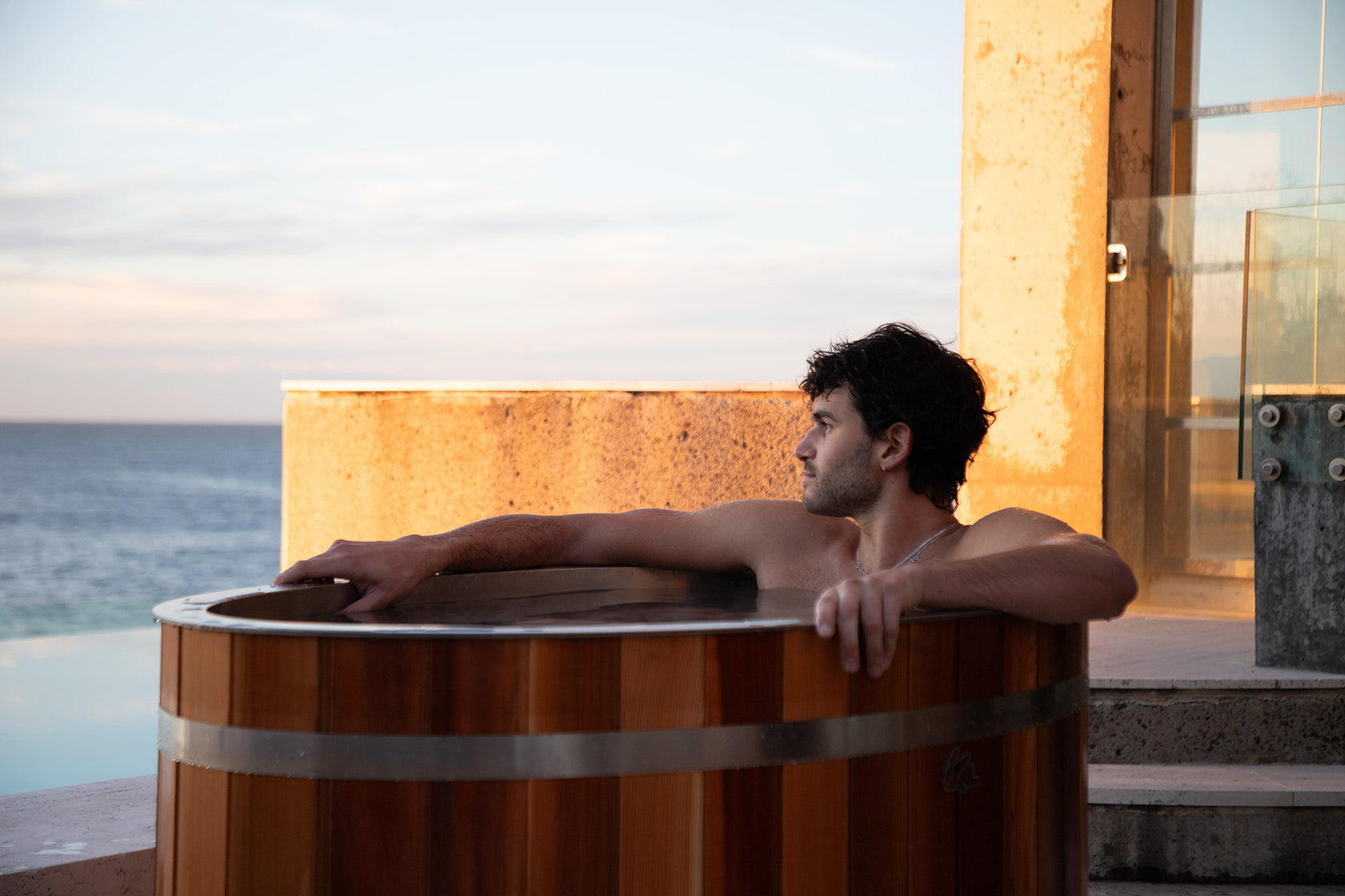 man in chill bunny ice bath outdoors - looking at ocean 